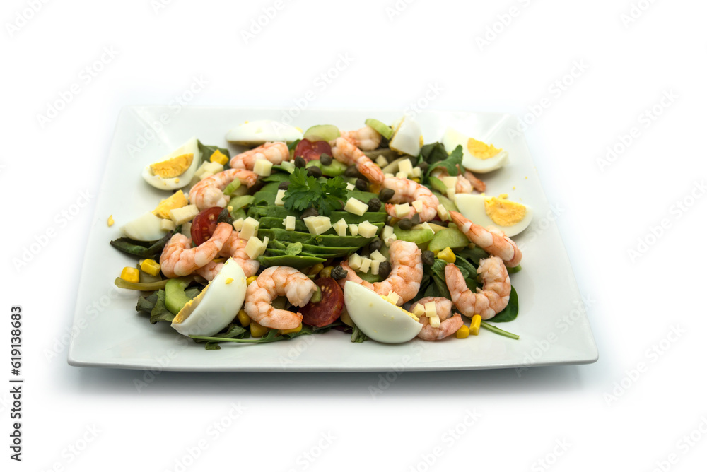 Closeup of avocado salade with shrimp in a white plate on white background