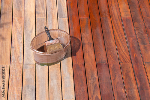Ipe wood deck renovation treatment and maintenance concept, paint brush on the bucket with oil
