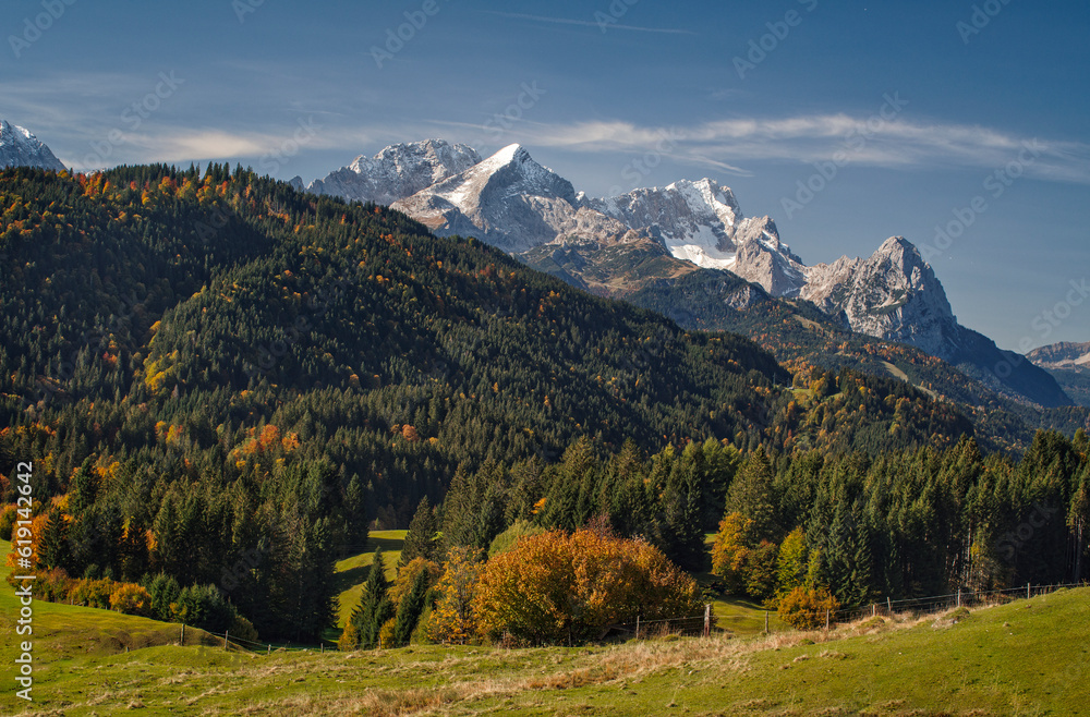 Herbststimmung in der Morgensonne im Voralpenland in den bayrischen Alpen mit Blick von einer Bergwiese auf Bergwälder und der Zugspitzen im Wettersteingebirge