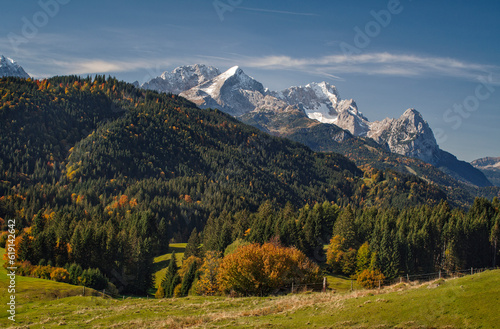 Herbststimmung in der Morgensonne im Voralpenland in den bayrischen Alpen mit Blick von einer Bergwiese auf Bergwälder und der Zugspitzen im Wettersteingebirge