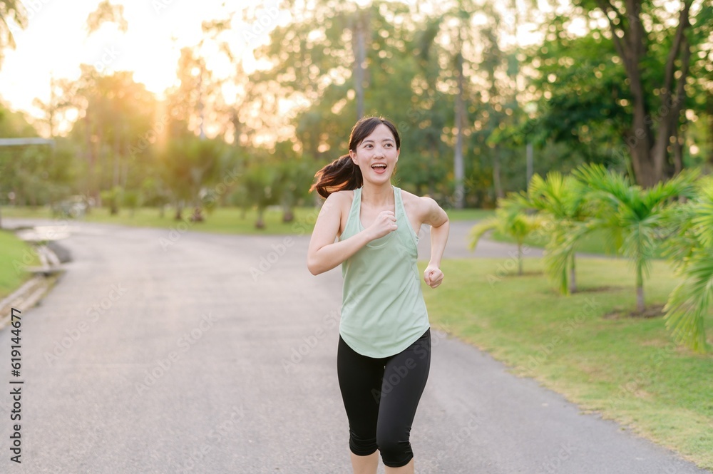 Fit Asian young woman jogging in park smiling happy running and enjoying a healthy outdoor lifestyle. Female jogger. Fitness runner girl in public park. healthy lifestyle and wellness being concept Fit Asian young woman jogging in park smiling happy running and enjoying a healthy outdoor lifestyle. Female jogger. Fitness runner girl in public park. healthy lifestyle and wellness being concept
