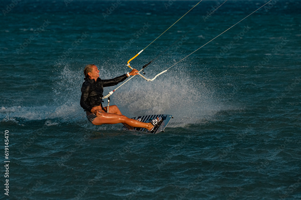 Kite surfing girl in sexy swimsuit with blue kite. Recreational activity, water sports, action, hobby and fun in summer time.