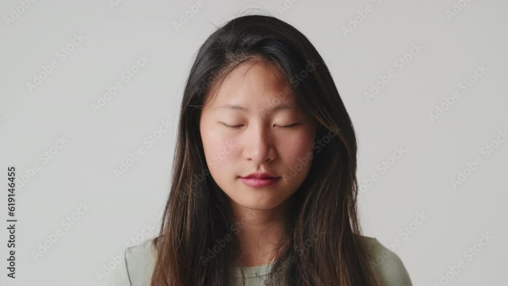Close up, young woman opens her eyes looking at camera, isolated over white background in studio Close up, young woman opens her eyes looking at camera, isolated over white background in studio