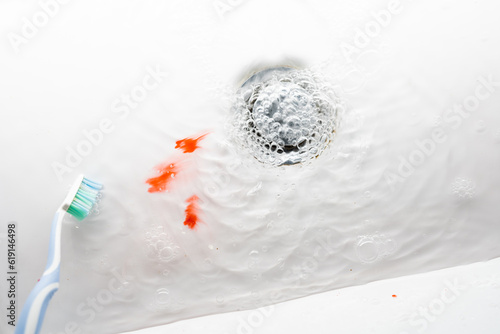 Toothbrush in a white washbasin with blood. Problem with gums. photo