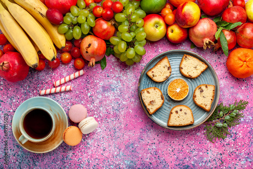 top view fresh fruit composition colorful fruits with cup of tea cakes and french macarons on pink desk fruit fresh mellow color ripe