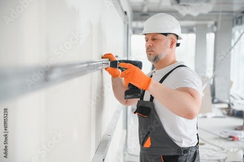 man fasten metal profile frame to the wall for draywall bulkhead. photo