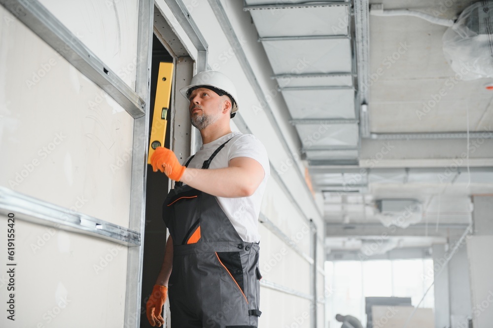 Man holding level against plasterboard, interior drywall. Attic renovation Man holding level against plasterboard, interior drywall. Attic renovation