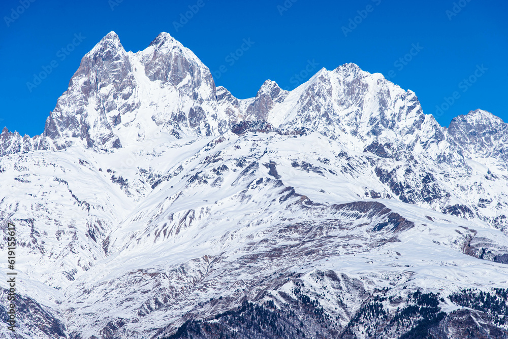 Beautiful panoramic view Ushba peak in Caucasus mountains covered with snow in winter and blue sky in Mestia Svaneti Georgia
