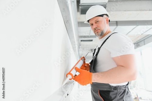 The builder fills the seams on the wall with sealed silicone
