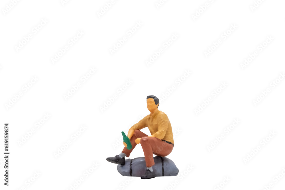 Miniature people Young man sitting on a rock isolated on white background with clipping path Miniature people Young man sitting on a rock isolated on white background with clipping path