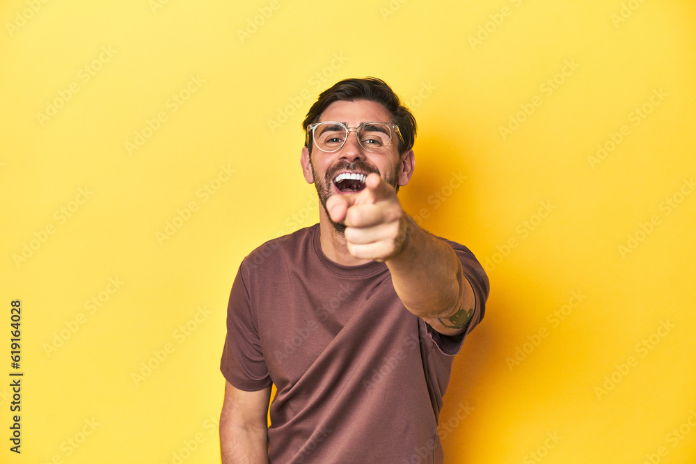 Man pointing and laughing at someone on a yellow studio background. Man pointing and laughing at someone on a yellow studio background.
