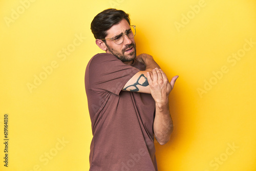 Fotografie Man stretching arm on a yellow studio background.