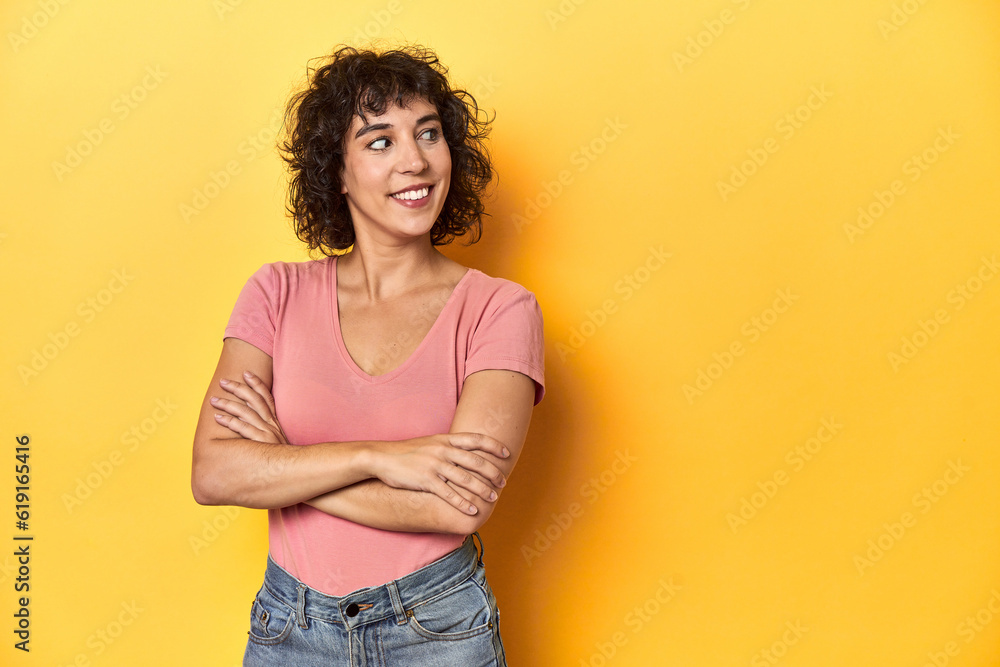 Curly-haired Caucasian woman in pink t-shirt smiling confident with crossed arms. Curly-haired Caucasian woman in pink t-shirt smiling confident with crossed arms.