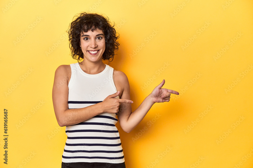 Caucasian curly-haired woman in white tank-top excited pointing with forefingers away. Caucasian curly-haired woman in white tank-top excited pointing with forefingers away.