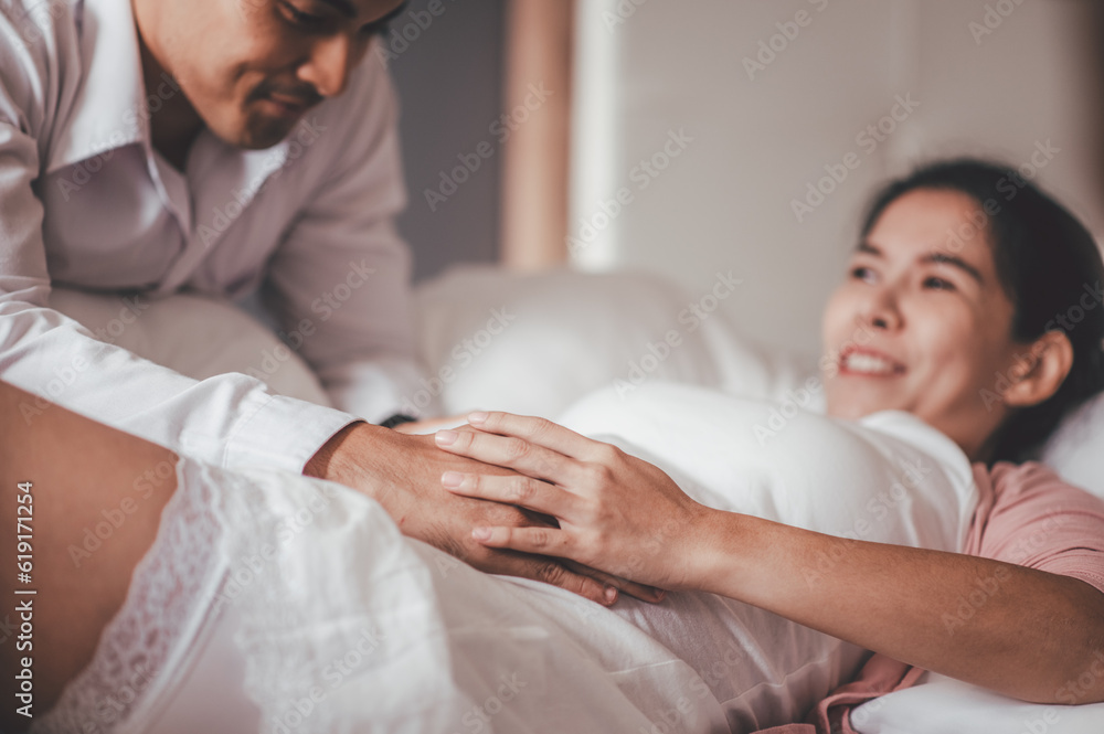 Obraz premium Love of family, motherhood, parenthood and expectation concepts. Asian woman and husband caressing his girlfriend belly and feeling the movements of the baby.