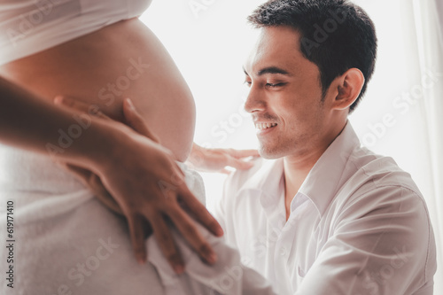 Concept Maternity and Pregnant, Prenatal care and pregnancy. Love of family, motherhood. Pregnant woman and her husband touch and look at the belly side windows at home.