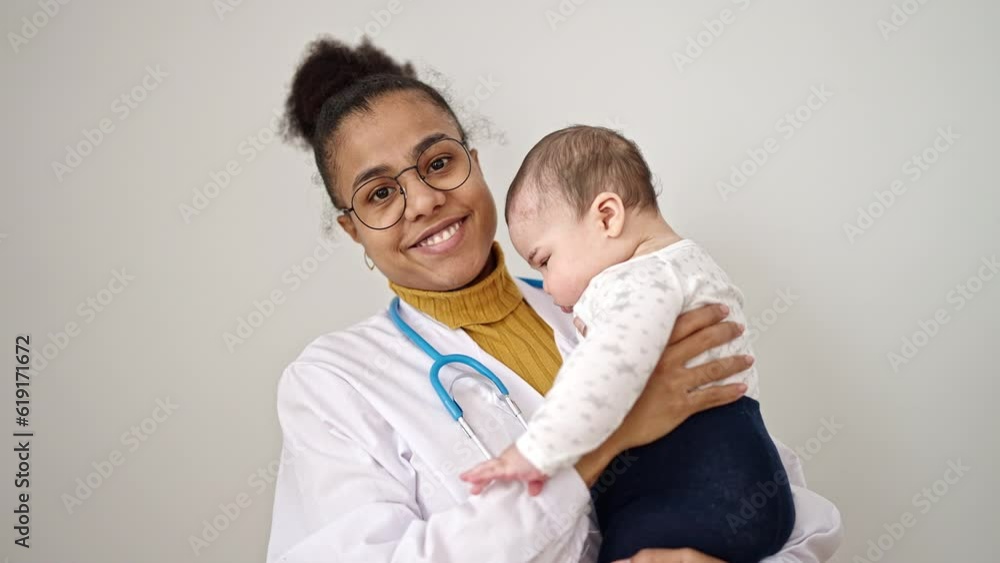 Young african american woman doctor smiling holding baby at clinic Young african american woman doctor smiling holding baby at clinic