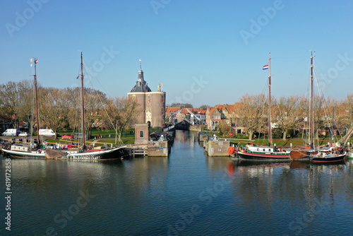 Drone photo of the old lock in Enkhuizen with the drommedaris tower in the background and a wooden sailing boats in the front.