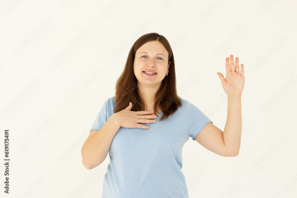 Smiling girl introduce herself, raising hand up and say hello. Woman telling truth, swearing she is honest, making promise with palm on heart, white background. Smiling girl introduce herself, raising hand up and say hello. Woman telling truth, swearing she is honest, making promise with palm on heart, white background.