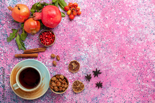 top view fresh pomegranate with green leaves and cup of tea on the pink background fruit fresh mellow autumn tree plant color