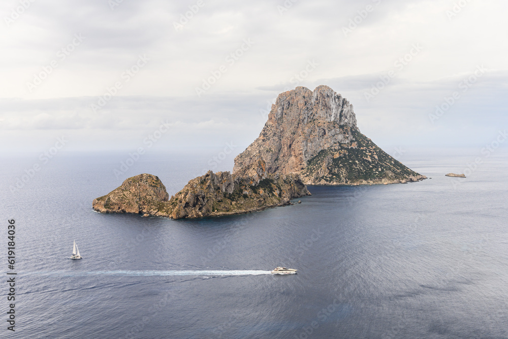 Ibiza landmark Es Vedra on a cloudy day with boat and yacht sailing by