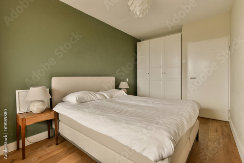 a bedroom with a white bed and green wall behind the bed is made up to look like a headboard