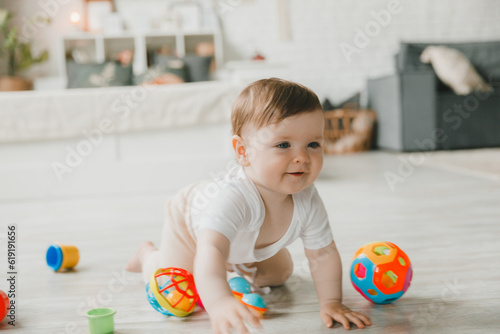 baby 6-9 months old playing with a colorful rainbow toy pyramid sitting in a white sunny bedroom. Toys for small children. Children's interior. A child with an educational toy.