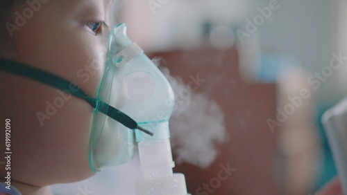 A little boy having a medicine inhalation with a nebulizer mask in the hospital. photo
