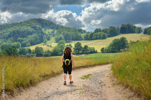 Junge Frau auf einer Wanderung im idyllischen Hügelland des Odenwaldes, Hessen, Deutschland, Sommer 2023