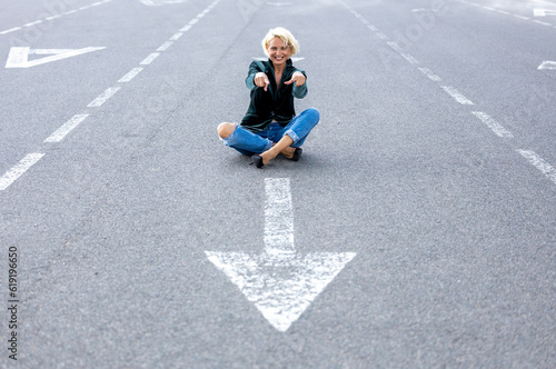 Blonde adult woman posing with a good mood on a road sign
