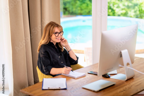 Obraz na plátně Attractive mid aged woman sitting at home and using compter for work