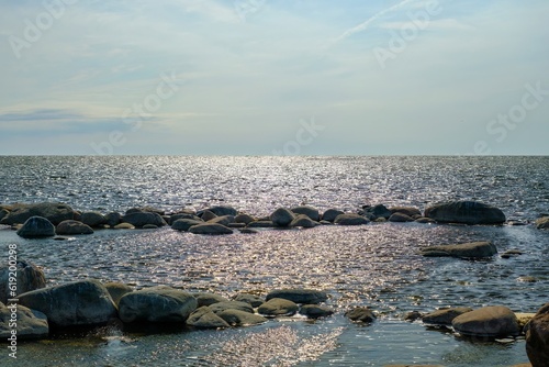 By the sea and sea view. Stones on the shore and in the water. View of the sea and bright blue sky.