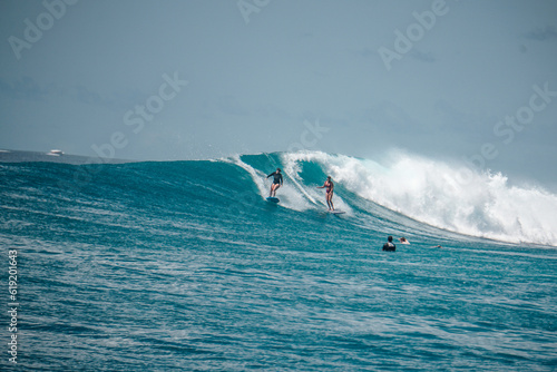 Two Surfer girls on long boards on perfect blue aquamarine wave together, party wave, empty line up, perfect for surfing, clean water, Indian Ocean, Maldives