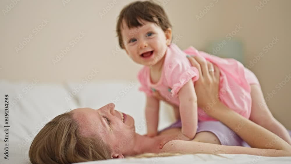 Mother and daughter lying on bed smiling at bedroom Mother and daughter lying on bed smiling at bedroom