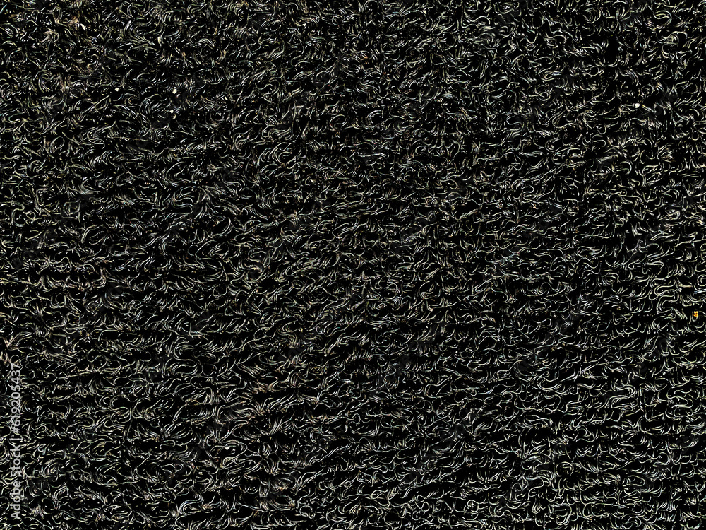 Fototapeta premium PVC coil floor mat closeup, a texture for background. Black vinyl loop mat for car floor, or non-slip doormat. Surface of industrial heavy duty matting, dirt or dust trap. Drainage indoor/outdoor mat.