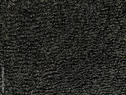 PVC coil floor mat closeup, a texture for background. Black vinyl loop mat for car floor, or non-slip doormat. Surface of industrial heavy duty matting, dirt or dust trap. Drainage indoor/outdoor mat.