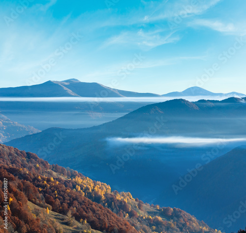 Colorful forest on autumn slope and clouds between the peaks (Carpathian, Ukraine).