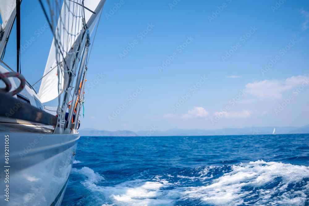 Fototapeta premium Yacht sailing in an open sea. Close-up view of side of the boat. Clear sky after the rain, waves and water splashes