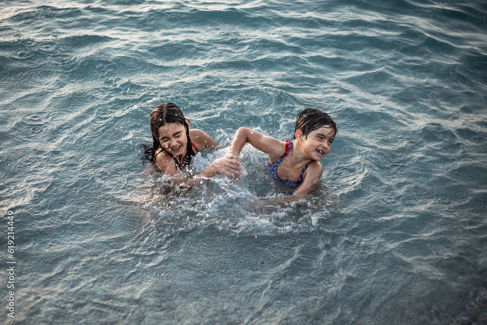 upper view on two smiling girls playing in the blue sea
