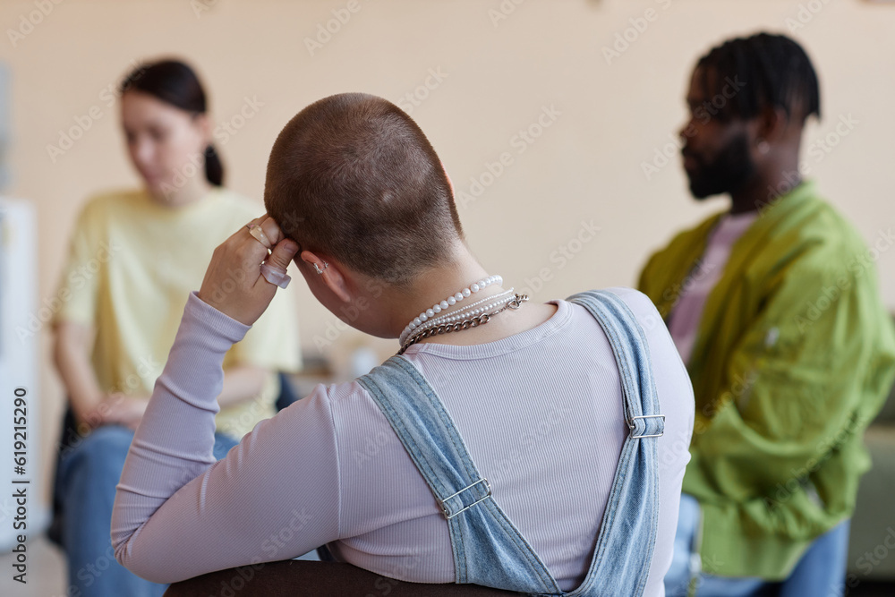 Fototapeta premium Rear view of shaved woman sitting with group at psychotherapy session in office