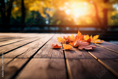 Wooden table with fallen leaves during autumn with background of trees of different autumn colors