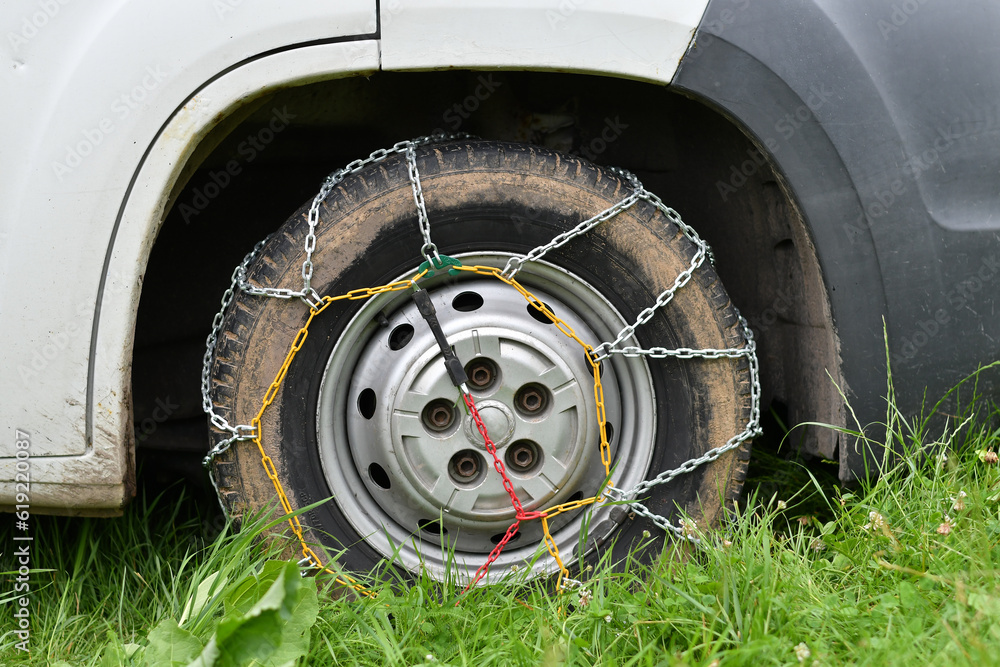 A car wheel wrapped with anti slip chain for climbing up dirt road. Close-up. A car wheel wrapped with anti slip chain for climbing up dirt road. Close-up.