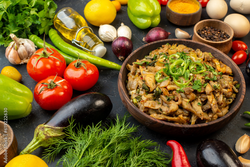 Horizontal view of delicious eggplant meal fresh vegetables spices fallen oil bottle green bundle on dark color background