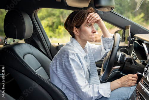 Stressed middle aged woman driving car having problems on road looking ahead. Nervous female feeling fear, fright, aggression standing in traffic jam on rush hour. Exhausted frustrated shocked driver.