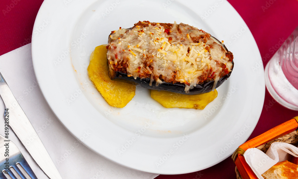 Image of a appetizing stuffed eggplant with cheese baked on top, served on chopped potatoes