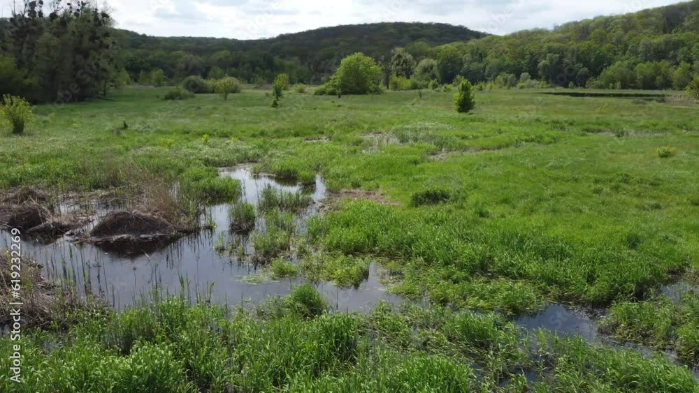 Drone flight over sleepy meadows with slight flooding. Gradually moving away to take the green hills into the lens. Drone flight over sleepy meadows with slight flooding. Gradually moving away to take the green hills into the lens.