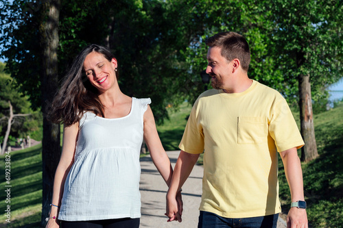 Happy couple in expectance walking in park photo