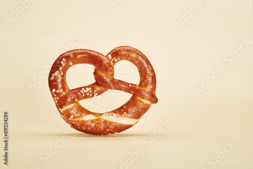 Appetizing traditional Bavarian pretzel baked bun isolated on the bright solid fond plain yellow background