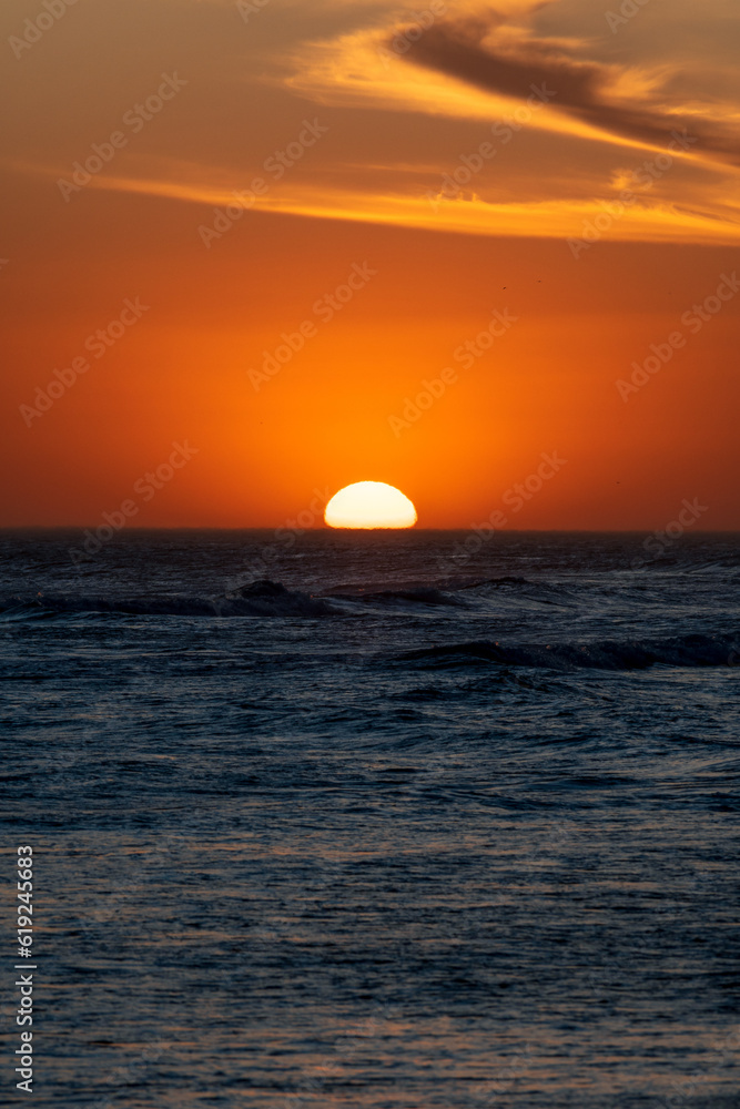 Sun setting in the sea with beautiful cloud arrangement. Concepts of calm and vacation.