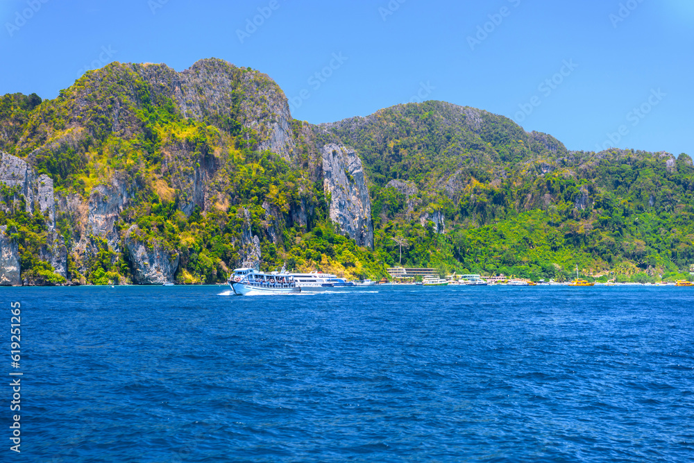 Motor ship in the bay of Ko Phi Phi Don Island with huge rocks and cliffs on a sunny day, Ao Nang, Mueang Krabi District, Krabi, Andaman Sea, Thailand